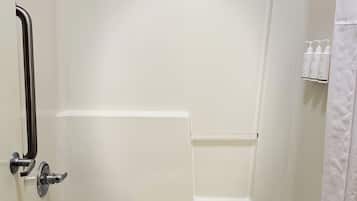 A white bathtub with a showerhead, a towel, and a shelf with toiletries.