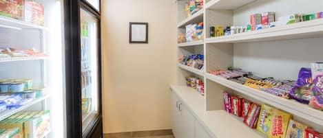 A refrigerated section with various dairy products and a shelf stocked with snacks and candies.