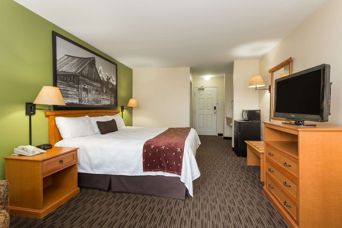 Ein Hotelzimmer mit Bett, Nachttischlampen, Fernseher, Schreibtisch und Telefon.