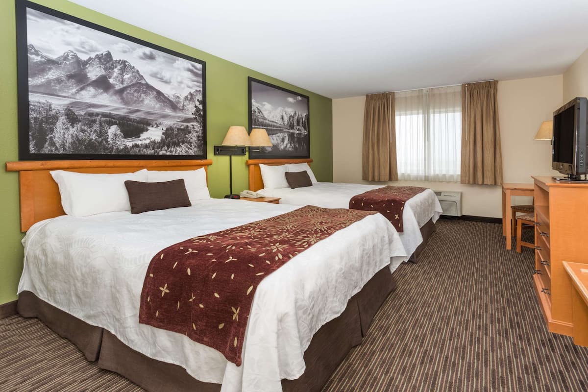 Ein Hotelzimmer mit zwei Betten, einem Schreibtisch und einem Fernseher.