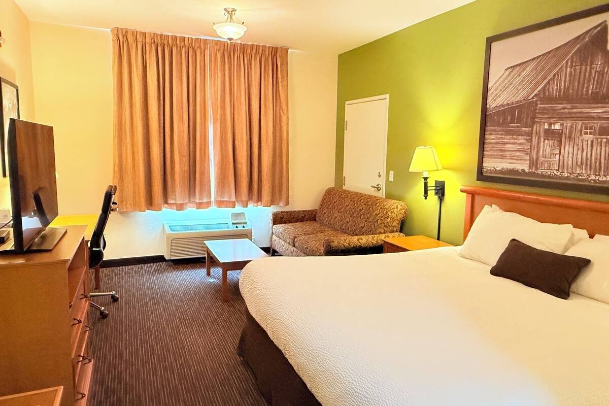 Ein Hotelzimmer mit Bett, Schreibtisch, Stuhl, Lampe und einem Bild an der Wand.