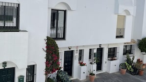 Un edificio blanco con balcones, una puerta y macetas.