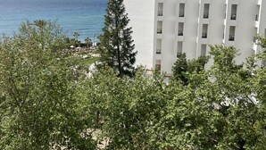 A high-rise hotel with multiple balconies overlooking a clear blue sea.