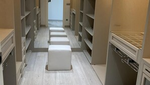 A narrow walk-through closet with multiple shelves and a central bench.