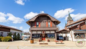 A building with a brown facade and a large window display. - Charming Downtown Two Bedroom w/ Fireplace (New Glarus)