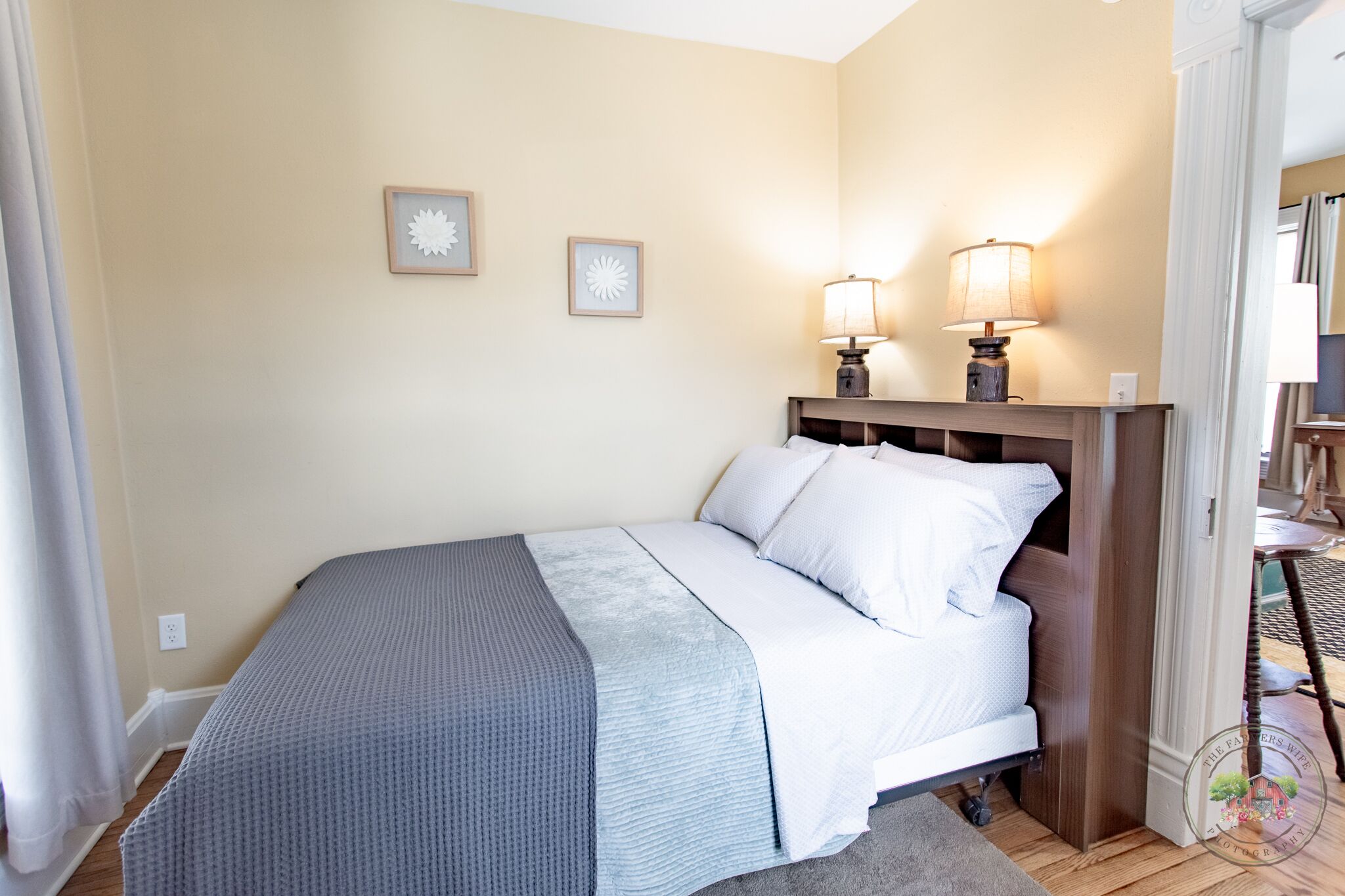 Une chambre à coucher avec un lit, deux lampes fixées au mur et deux tableaux encadrés.