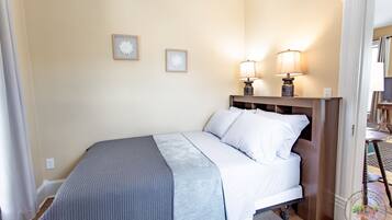 Une chambre à coucher avec un lit, deux lampes fixées au mur et deux tableaux encadrés.