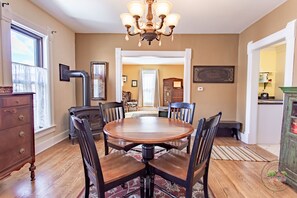 A dining room with a wooden table and chairs, a chandelier, and a view to another room. - Charming Downtown Two Bedroom w/ Fireplace (New Glarus)