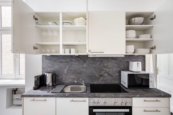 Enjoy cooking and baking in this well-equipped kitchen with stainless steel appliances, open shelving, and a convenient backsplash.