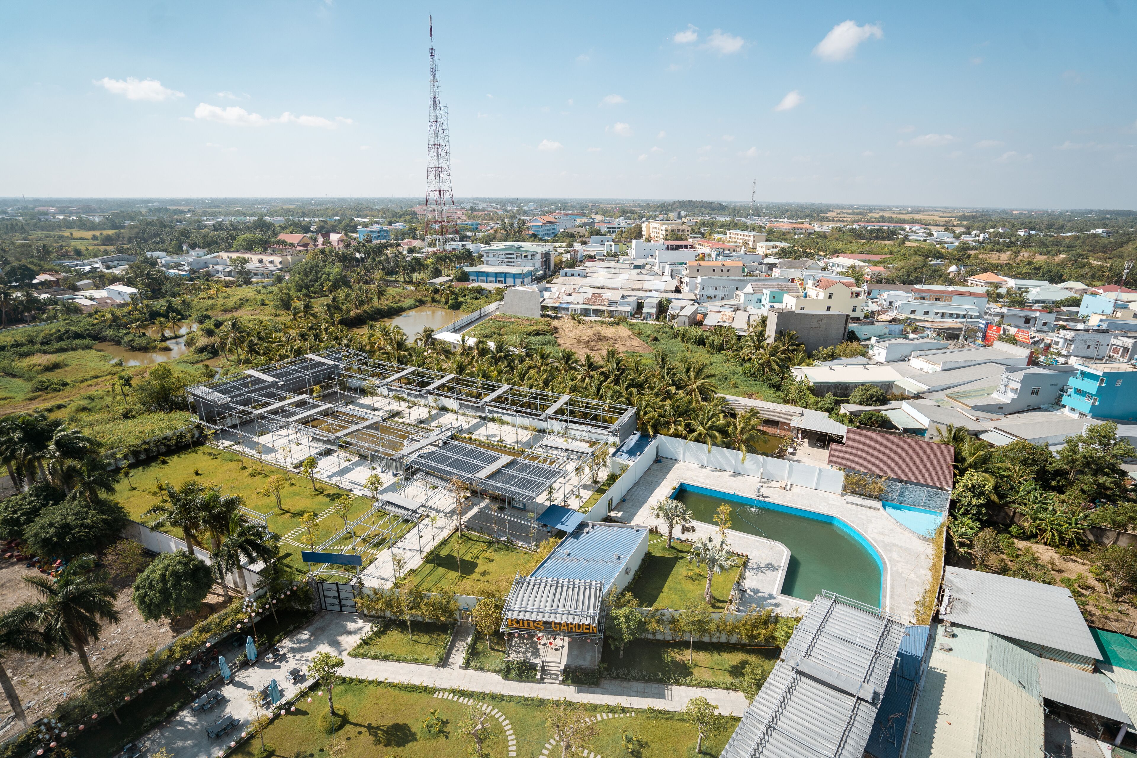 Vue aérienne d’un complexe hôtelier comprenant plusieurs bâtiments, une piscine et de nombreux espaces verts.