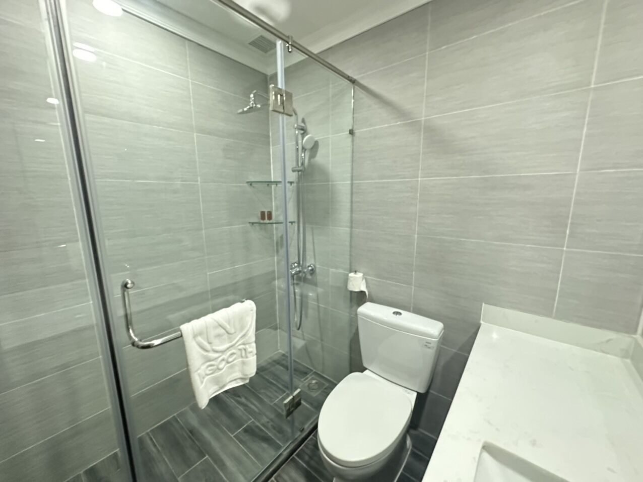 Un baño moderno con cabina de ducha de vidrio, inodoro blanco y lavamanos blanco.