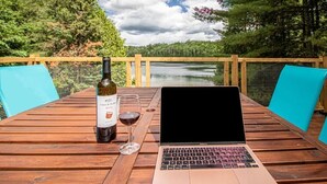 A wooden table with a laptop, a wine bottle, and a glass of wine. - Peaceful Chalet on Pristine Lac de l'Abies in Labelle, QC. Dogs Welcome! (Labelle)