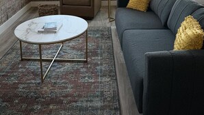 Ein Wohnzimmer mit einem braunen Ledersofa, einem grauen Sofa mit gelben Kissen, einem weißen Couchtisch und einem kleinen Beistelltisch.