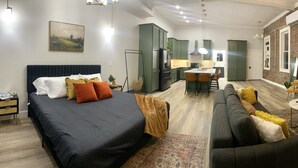 Eine moderne Wohnung mit einem großen Bett, einer Couch, einem Essbereich und einer Küche.