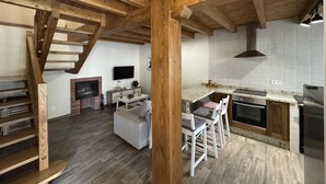 A spacious living area with a wooden staircase, a fireplace, a television, and a kitchen with a tiled backsplash and modern appliances. - Casa Moises Bimenes (Las Cruces)