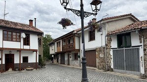 A cobblestone street with traditional buildings, a street lamp, and hanging flower baskets. - Casa Moises Bimenes (Las Cruces)