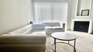 Ein Wohnzimmer mit einer Eckcouch, einem runden Couchtisch und einem Kamin.