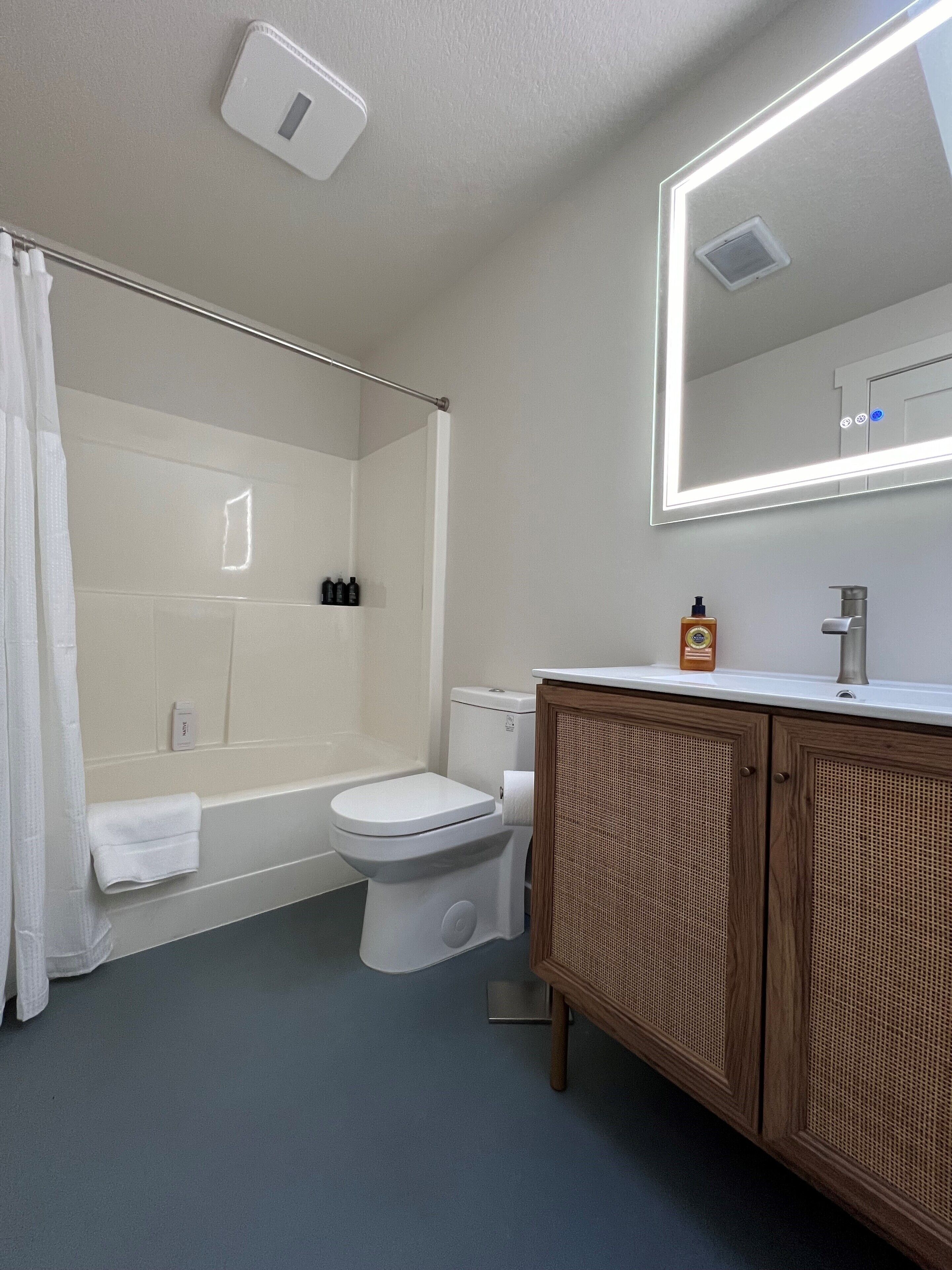 A bathroom with a bathtub, toilet, and a wooden cabinet.