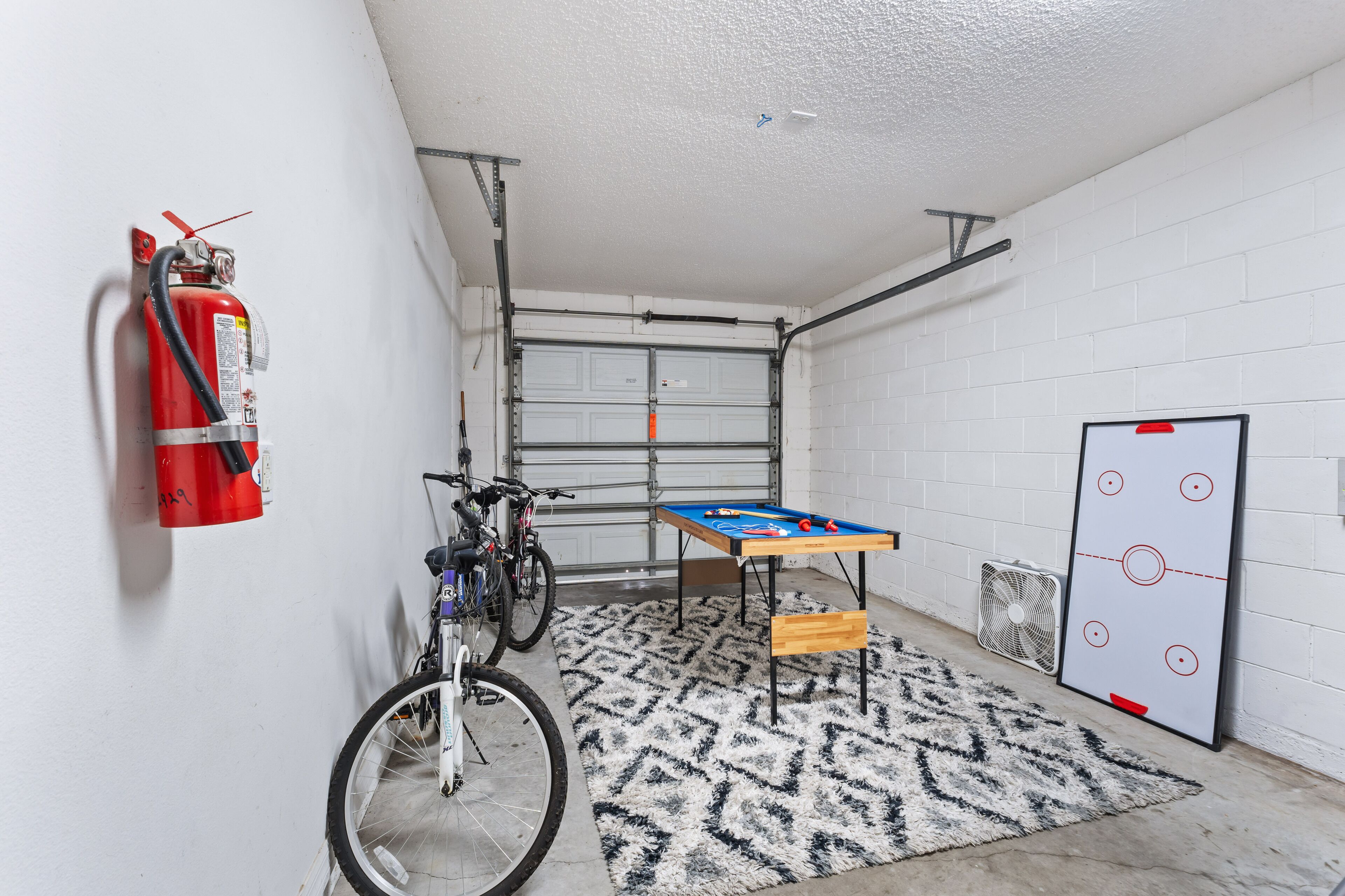 Un garage équipé d’un extincteur, d’un vélo, d’un baby-foot et d’un but de hockey.