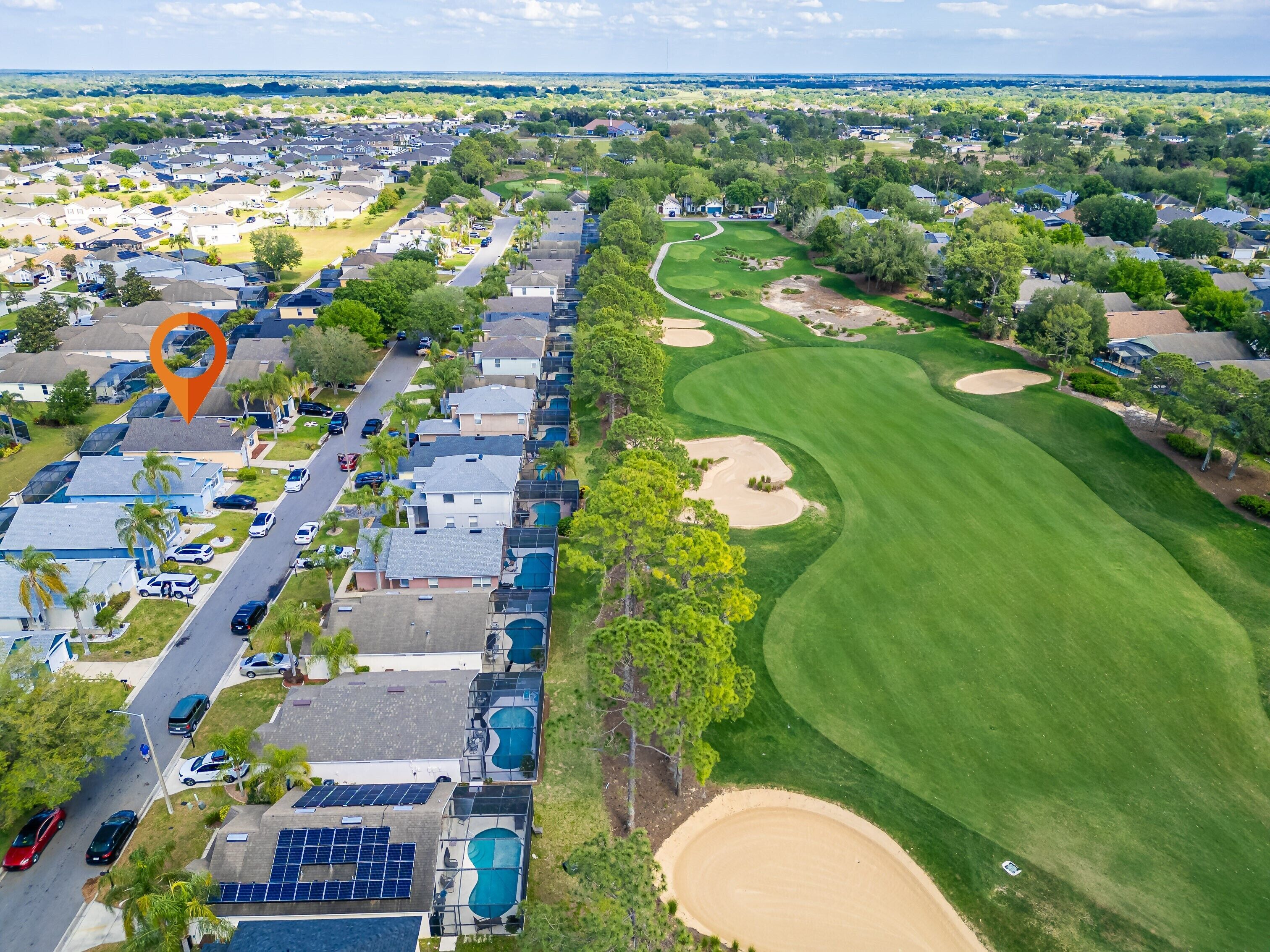 A residential area with houses, a road, and a golf course.