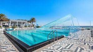 A pool with clear blue water, a covered area with lounge chairs, and a tiled deck. - The W Beachfront Blue Sanctuary (Fort Lauderdale)