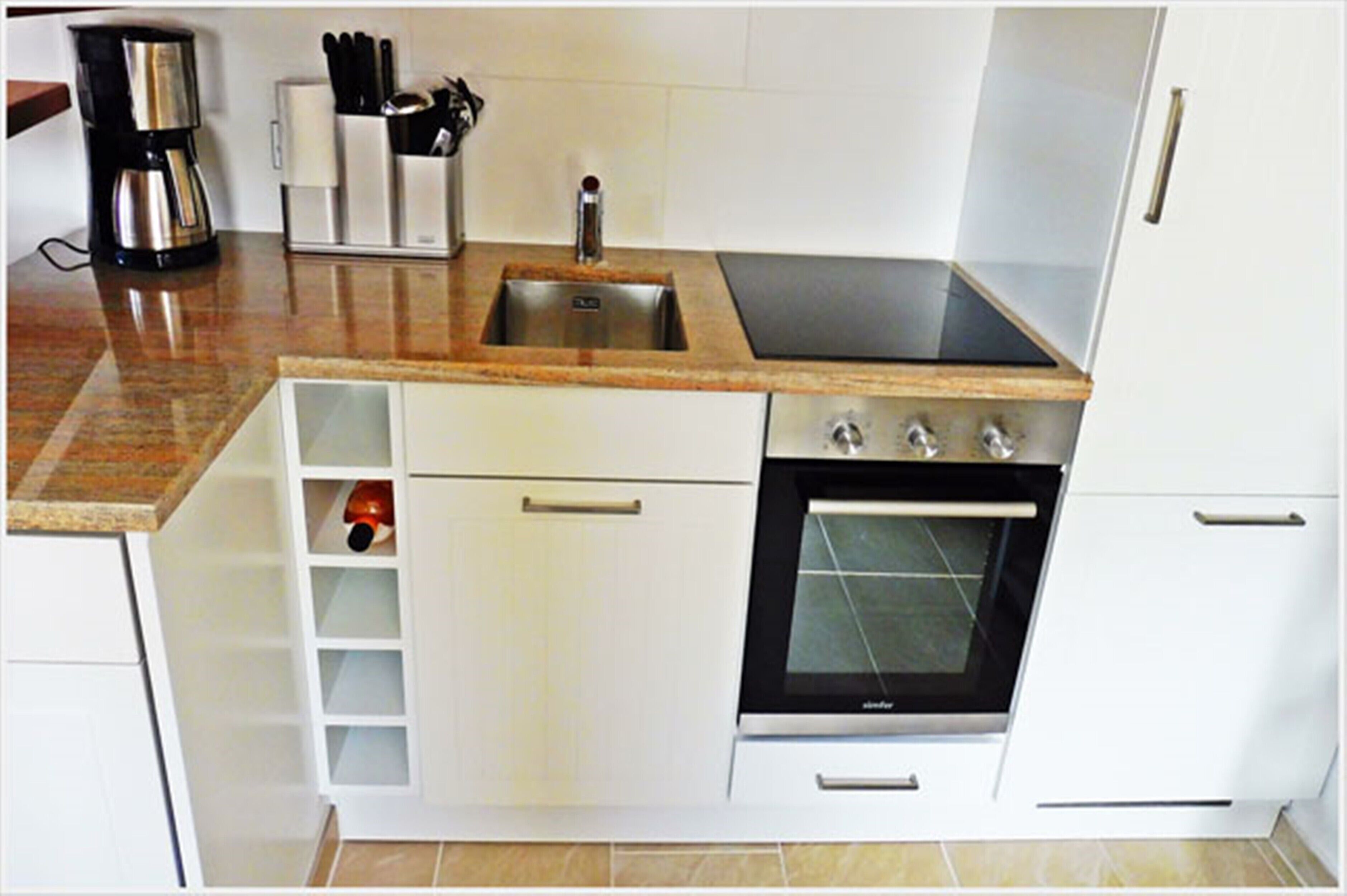 Cocina compacta con pileta, estufa y alacenas.