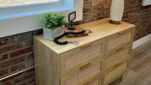 A wooden dresser with drawers, a lamp, a small plant, and a decorative item on top. - Loft Apartment On Main - Sleeps 4 (Du Quoin)