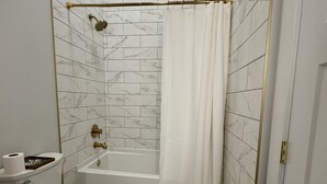 A bathroom with a toilet, bathtub, and shower curtain. - Loft Apartment On Main - Sleeps 4 (Du Quoin)