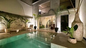 An indoor swimming pool with lounge chairs and potted plants. - Casa Koko - Luxury Oasis in Centro Merida (Mérida)