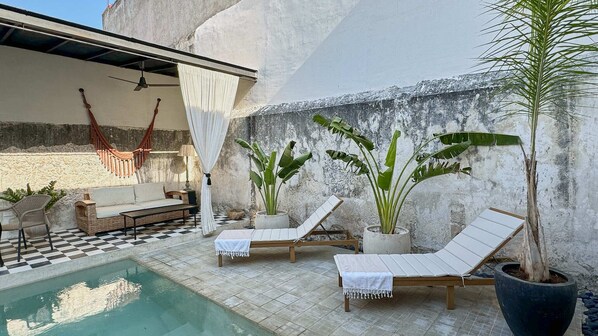 A poolside area with lounge chairs, a sofa, and potted plants. - Casa Koko - Luxury Oasis in Centro Merida (Mérida)
