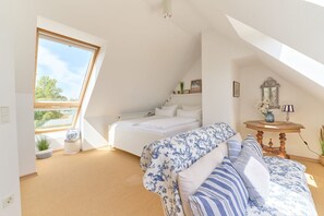 A bedroom with a skylight, a bed, a sofa, and a small table with decorative items. - Hanseaten Residenz - Sea Love Scharbeutz Gemütliche Ferienwohnung Über 2 Etagen für 4 Personen (Scharbeutz)