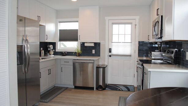 A modern kitchen with stainless steel appliances, white cabinetry, and a black tiled backsplash. - Beautiful, Modern, Quiet, Comfy & Private with a Big Back Yard - 30+ day stays  (Denver)