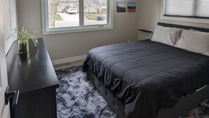 A bedroom with a bed, a ceiling fan, a window, and a desk with a plant. - Beautiful, Modern, Quiet, Comfy & Private with a Big Back Yard - 30+ day stays  (Denver)