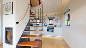 Une cuisine moderne avec des murs en briques blanches, un escalier en bois et une plante suspendue.