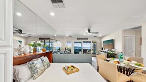 Una habitació d'hotel moderna amb un llit, zona de menjador i vistes a l'oceà.