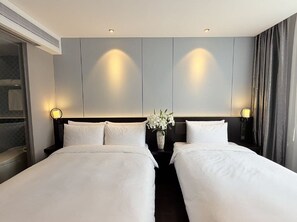 Habitación de hotel con dos camas, un ventanal grande y una lámpara fijada a la pared.
