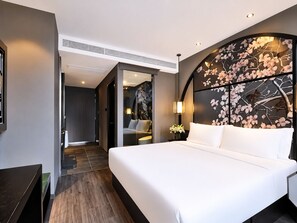 Moderni hotellihuone, jossa on suuri sänky, työpöytä, tuoli ja koristeellinen seinä, jossa on kukka-aiheisia kuvioita.