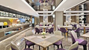 A modern restaurant with marble flooring, purple upholstered chairs, and a central dining table with a vase of flowers. - Crystal Hotel Shanghai The Bund Jinling (Shanghai)