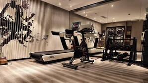 Un gimnasio con equipo de ejercicio, cinta de correr y un soporte para pesas.