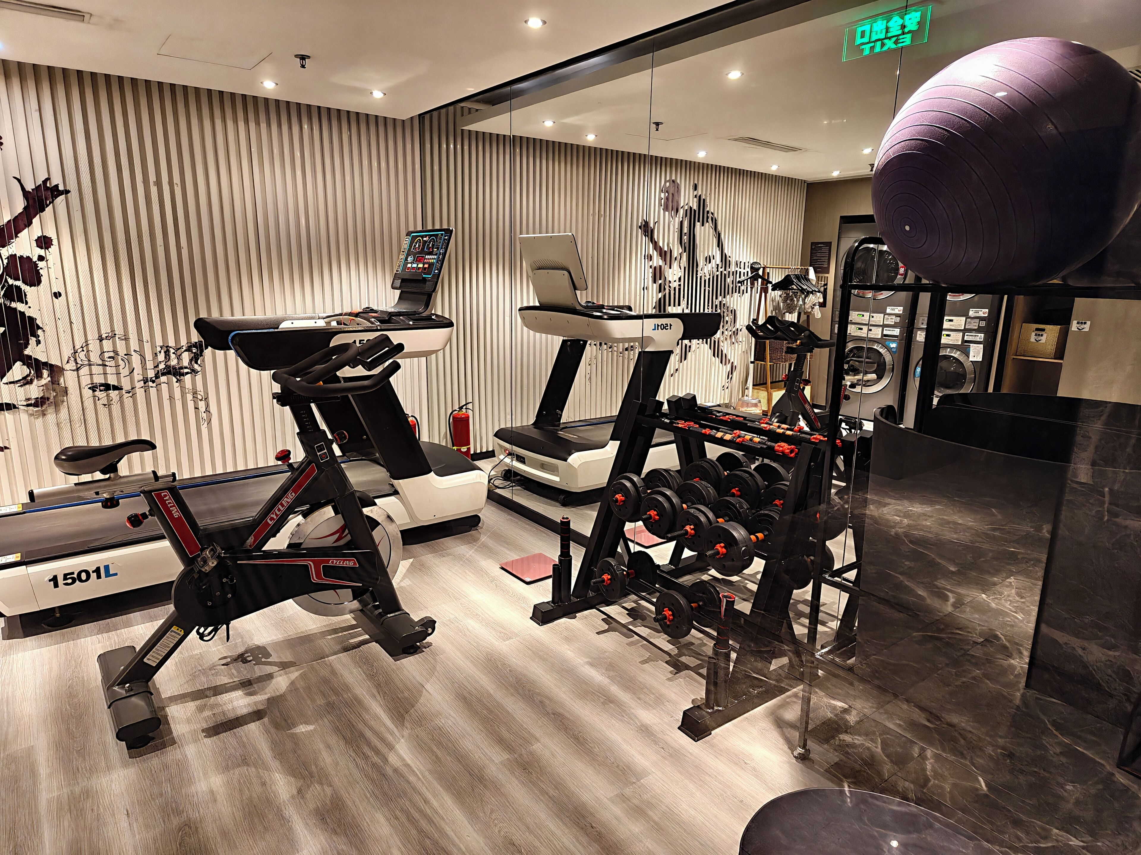 Ett gym med löpband, en motionscykel och en stång med vikter.