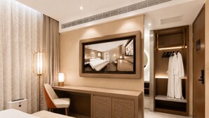 Una habitación de hotel con una cama, un escritorio, una silla, un espejo, un armario y una lámpara.