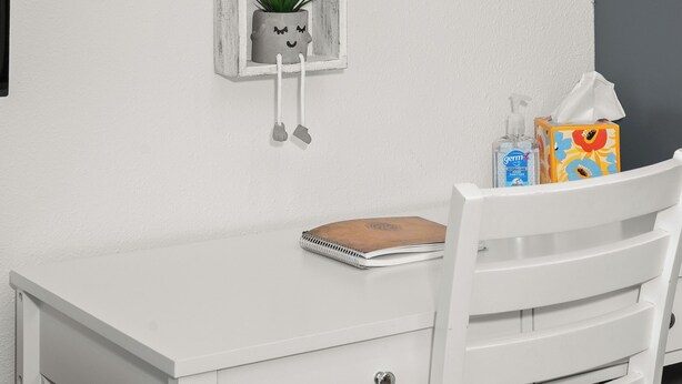 A white desk with a notebook, a small potted plant, and a tissue box. - Updated Spacious Home & Hot Tub (Spokane Valley)