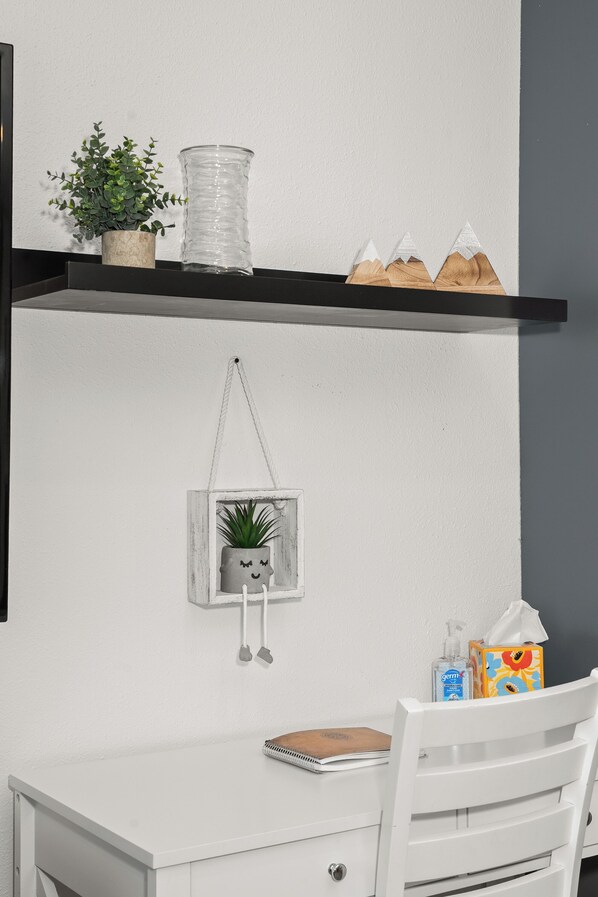 A white desk with a notebook, a small potted plant, and a tissue box.