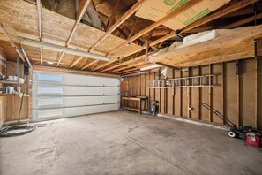 Un garaje con piso de concreto, vigas de madera y puerta de color blanco.