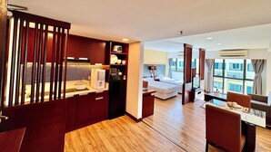 Una habitación de hotel moderna con kitchenette, zona de comedor y dormitorio con un ventanal grande.