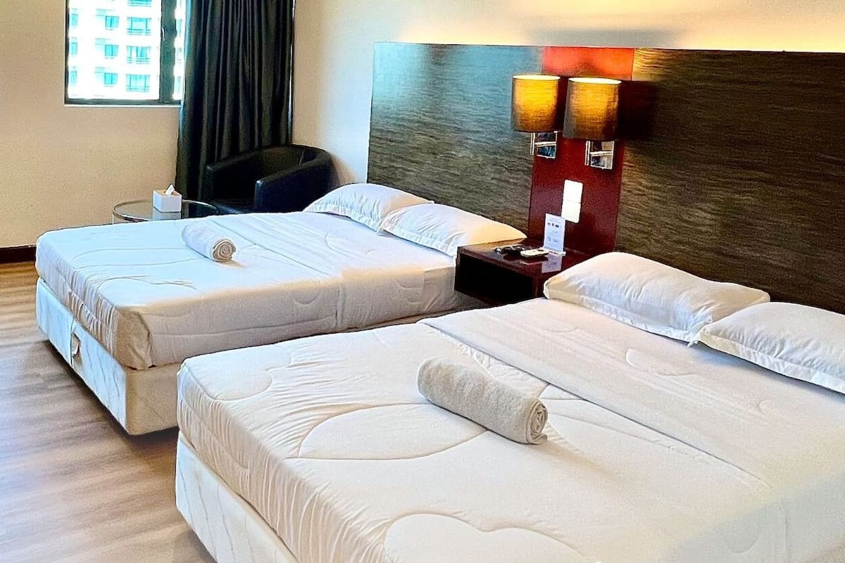 Una habitación de hotel con dos camas, un escritorio, una silla y una ventana con cortinas.
