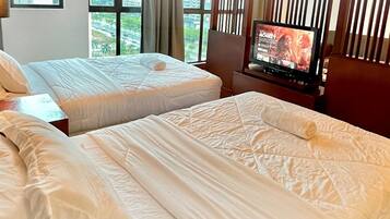 A hotel room with two beds, a TV, and a view of the city through large windows.