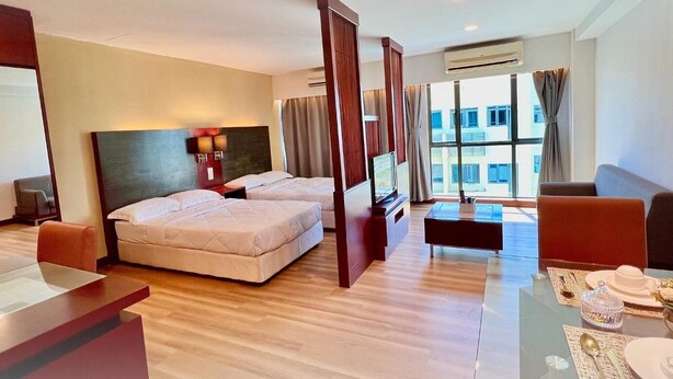 Habitación de hotel con dos camas, televisión, escritorio, mesa de comedor con sillas y un amplio ventanal con cortinas.