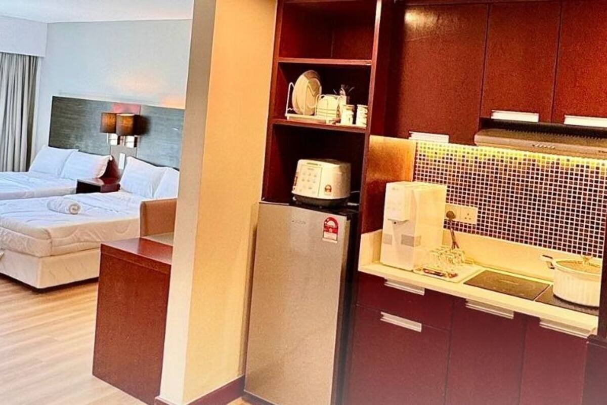 Habitación de hotel con cama, escritorio, silla, televisor y cocina equipada con microondas, con vistas al exterior.