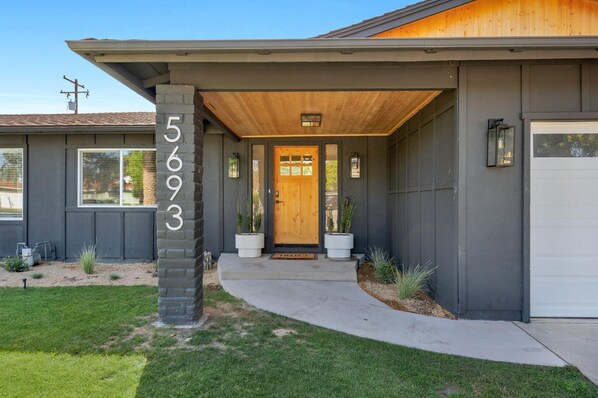 A modern house with a number '5693' on the front, a wooden front door, and a covered entryway. - Unique Modern Home W/Pool (Fresno)